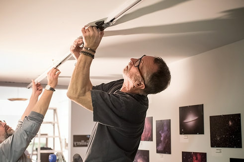 George Skarl installs track lighting in the Hallway Gallery