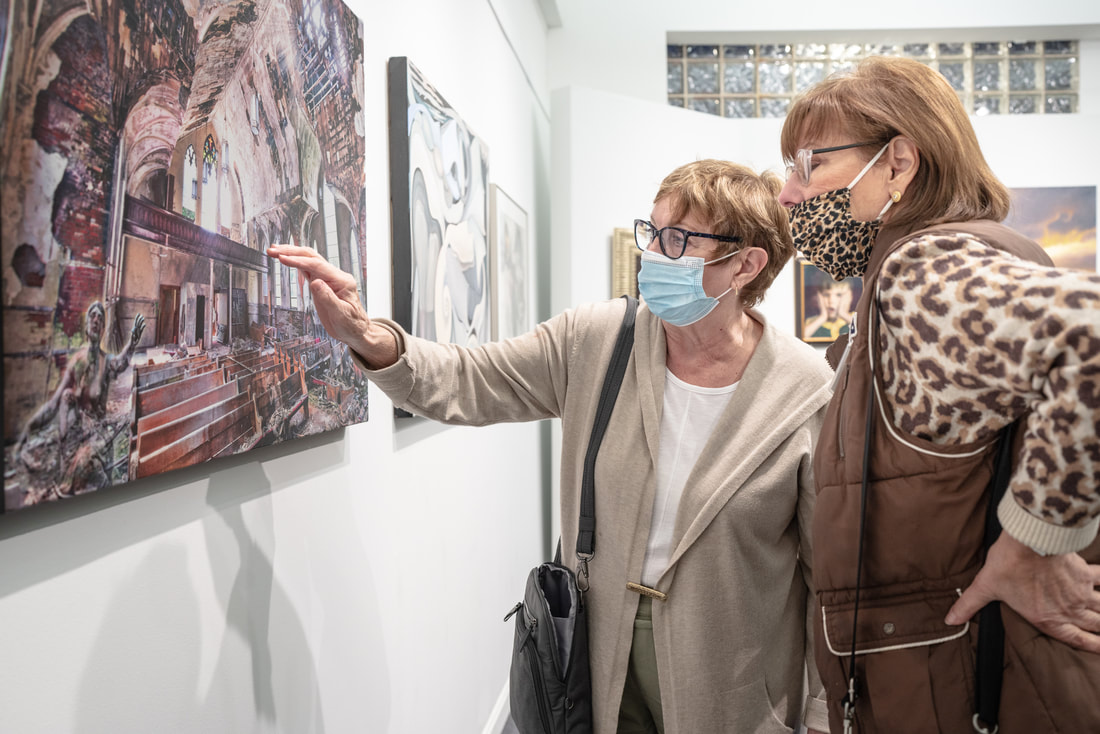KC Henry and Julie Cook discuss a work of art in the gallery